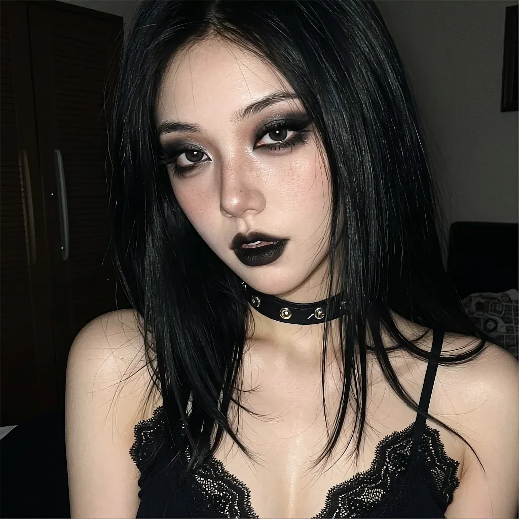Woman with long black hair and dark smoky makeup wearing leather choker and black lace camisole in dark bedroom